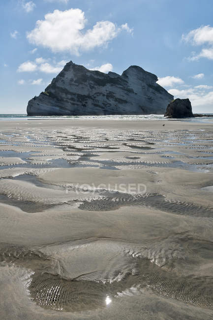 Новая Зеландия, Золотой залив, пляж Ухарарики, песок на пляже во время отлива и скалы — стоковое фото