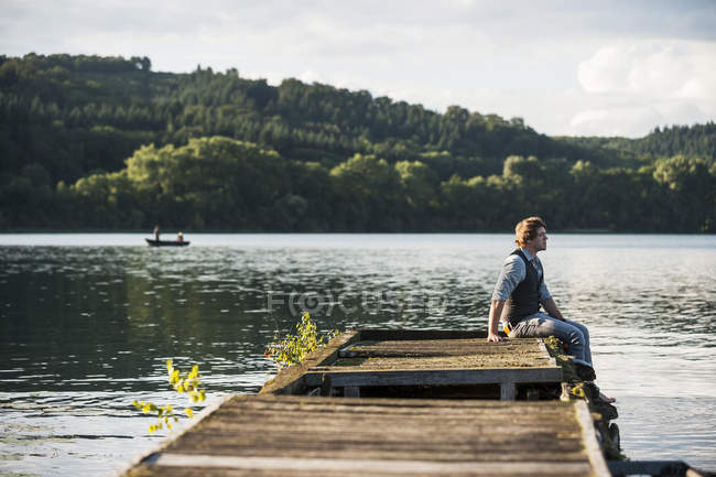 Alemanha, Renânia-Palatinado, Lago Laach, Homem sentado no calçadão de madeira — Fotografia de Stock