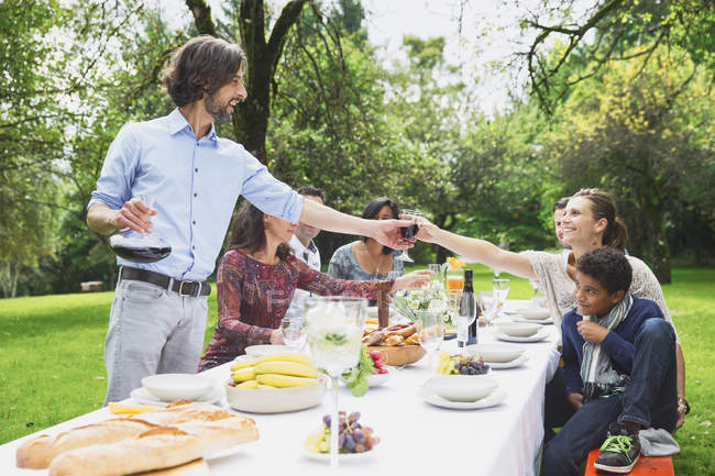 People pouring red wine on garden party — Stock Photo