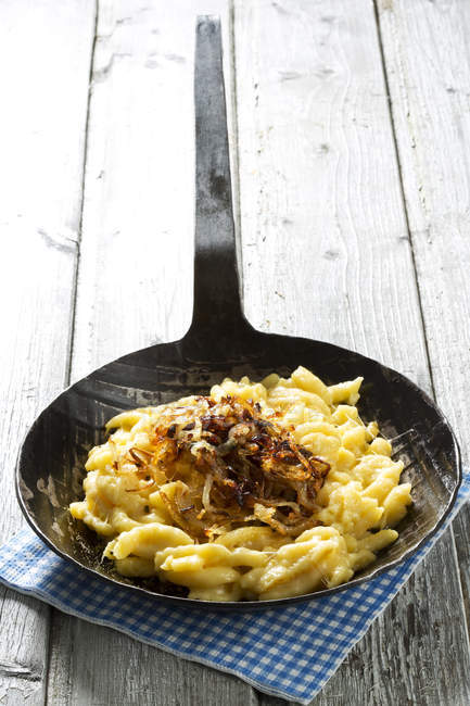Spaetzle au fromage et oignons rôtis dans une poêle sur la table, fermer — Photo de stock