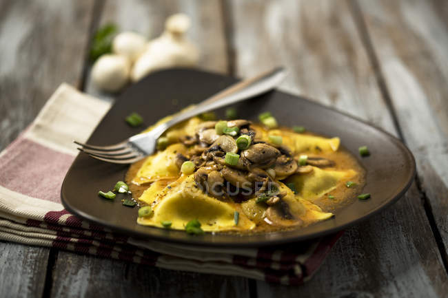 Ravioli con funghi sul piatto su superficie di legno — Foto stock
