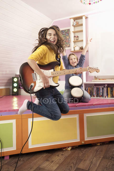 Дівчата стрибають граючи на гітарі — стокове фото