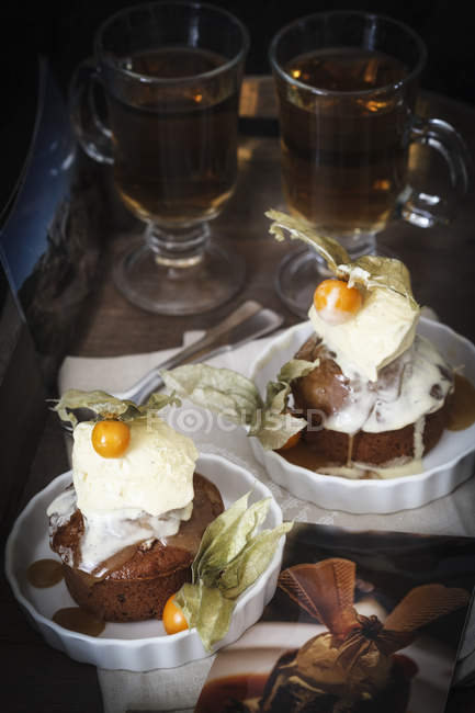 Budino caramellato appiccicoso con gelato alla vaniglia, physalis e tè sullo sfondo — Foto stock