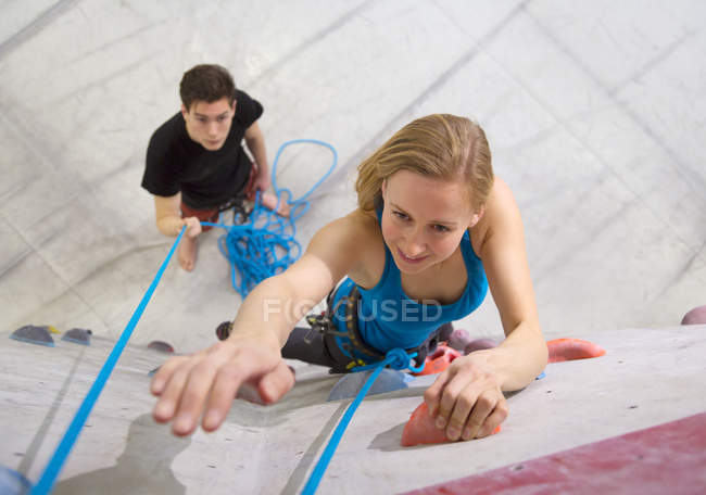 Giovane donna bouldering mentre l'uomo tiene la corda — Foto stock