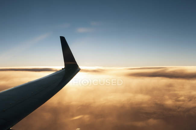 Крыло самолета над облаком на закате — стоковое фото