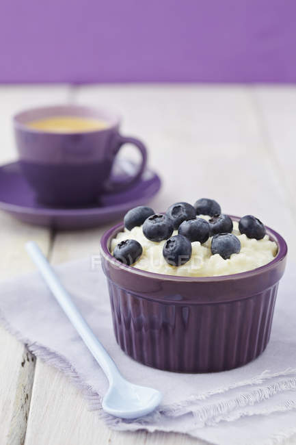 Bowl of milk rice pudding with blueberries and coffee in background — Stock Photo
