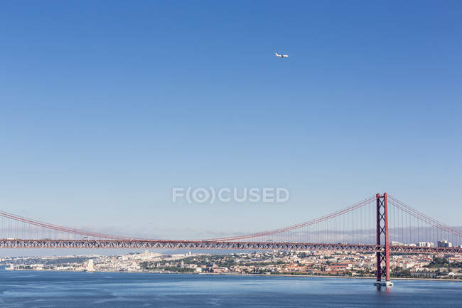 Bridge at River Tagus, airplane above cityscape — Stock Photo