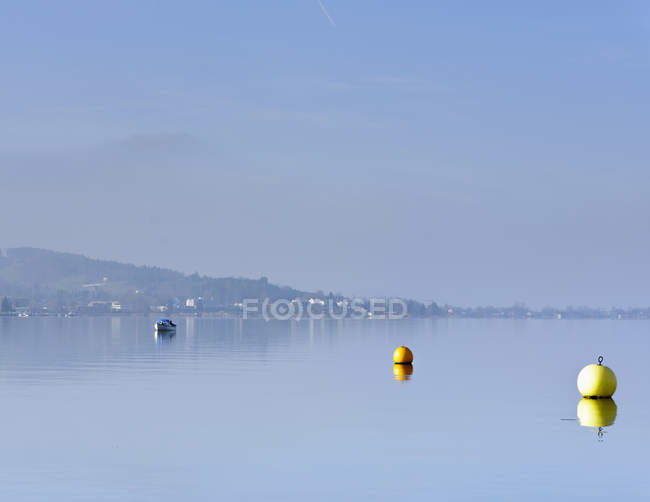 Switzerland, Lachen, Buoys and fishing boat on Lake Zurich — Stock Photo