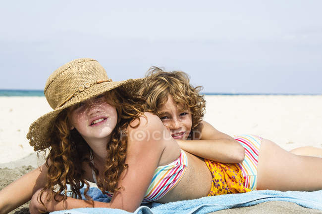 Hermano y hermana acostados en la playa - foto de stock