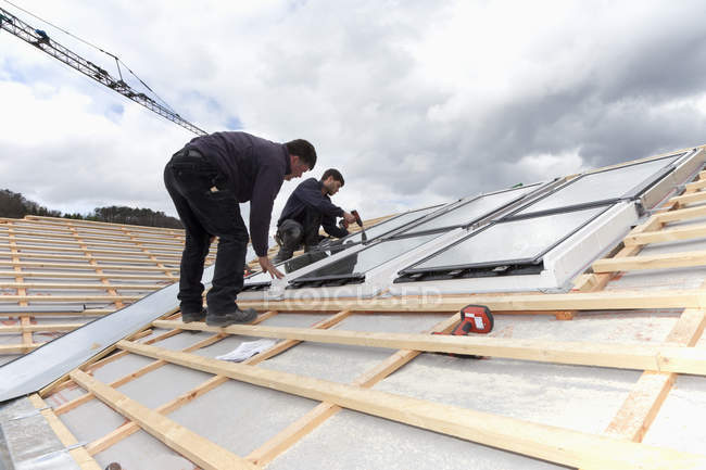 Trabajadores instalando ventanas de techo de la casa - foto de stock