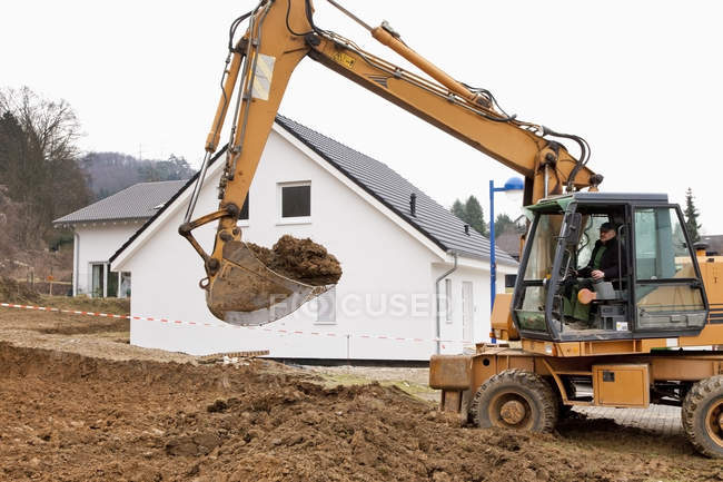 Man removing soil for house foundation with excavation vehicle — Stock Photo