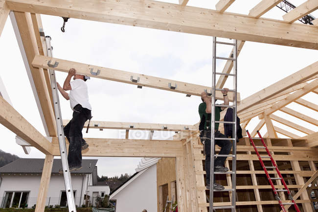 Hommes travaillant sur le toit de la maison sur le chantier — Photo de stock