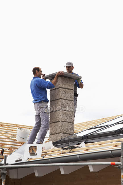 Trabalhadores instalando chaminé no telhado — Fotografia de Stock