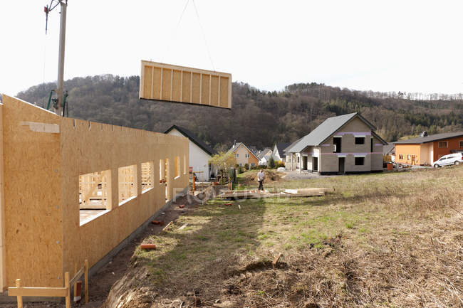 Hombre instalando y fijando paredes de madera de la casa prefabricada - foto de stock