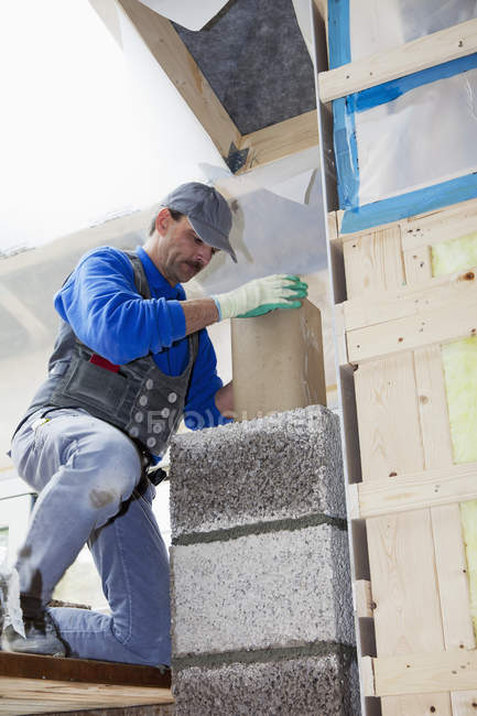 Male worker installing thermal insulation at construction site — Stock Photo