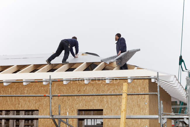 Trabalhadores manuais telhados em casa de madeira — Fotografia de Stock