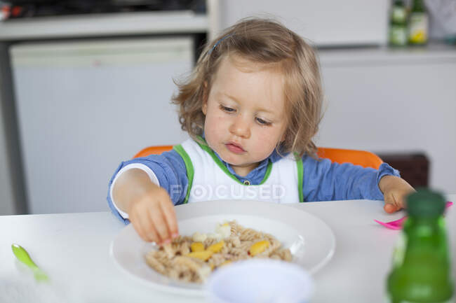 Дівчинка їсть локшину руками. — стокове фото