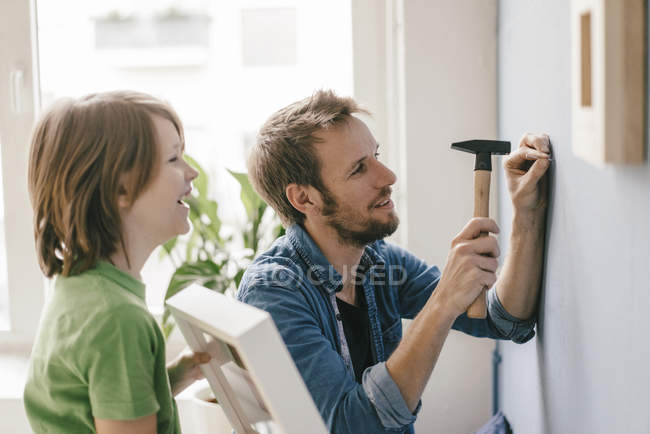Son watching father driving nail into wall at home — boy, tool - Stock  Photo | #258106808