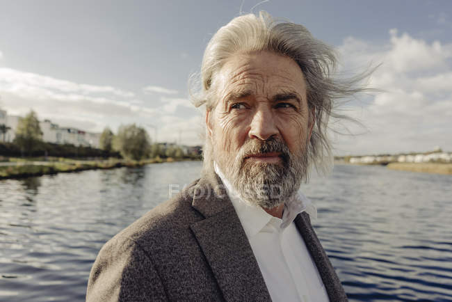 Retrato de un hombre mayor serio en el lago - foto de stock