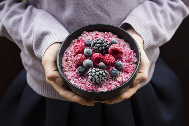Girl holding bowl with overnight oats mit frozen berries — Stock Photo