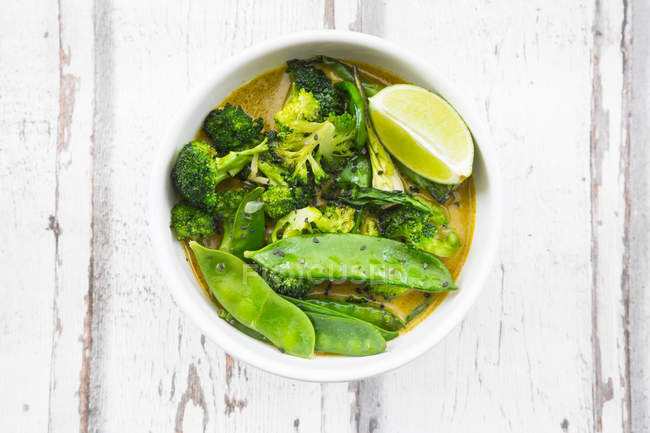 Curry tailandés verde con brócoli, pak choi, guisantes de nieve, espinacas bebé, lima y arroz - foto de stock