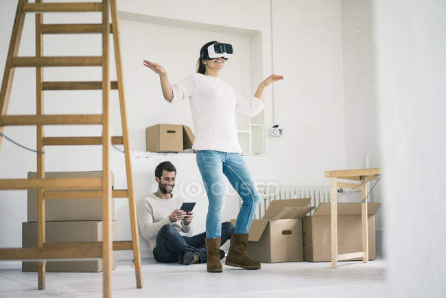 Couple in new home with woman wearing VR glasses — Stock Photo