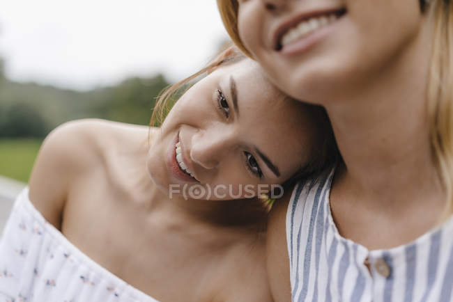 Sorridente giovane donna che riposa sulla spalla di un amico femminile — Foto stock