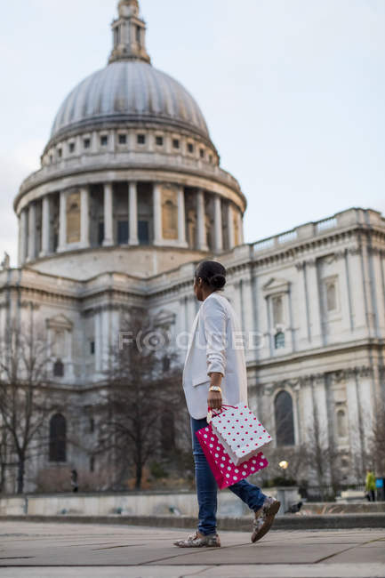 UK, London, woman walking with shopping bags at St Paul's Cathedral — Stock Photo