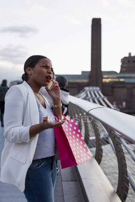 Великобритания, Лондон, раздраженная женщина с сумками для покупок по мобильному телефону в городе — стоковое фото