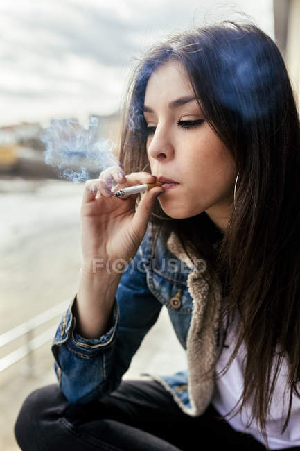 Mujer joven fumando un cigarrillo al aire libre - foto de stock