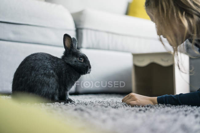 Ragazza con coniglio in soggiorno — Foto stock