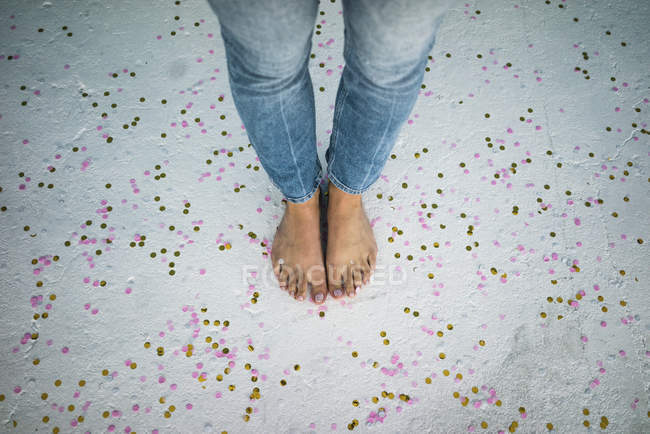 Cropped image of woman standing on confetti on floor — Stock Photo