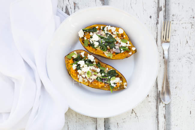 Filled sweet potato with spinach, red onion, couscous, feta and coriander — Stock Photo