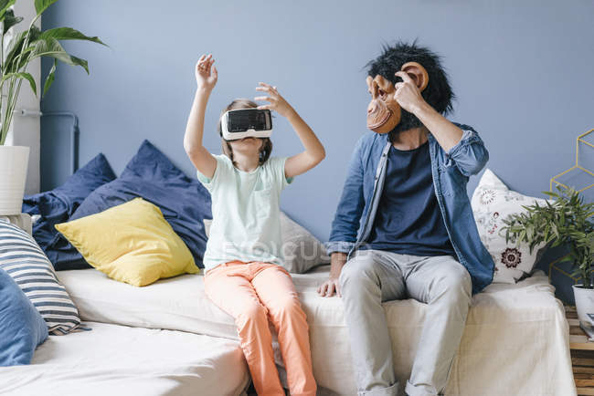 Батько в мавпці дивиться на сина в окулярах VR вдома — стокове фото