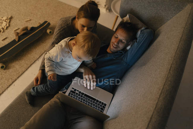 Семья с ноутбуком на диване в темноте — стоковое фото