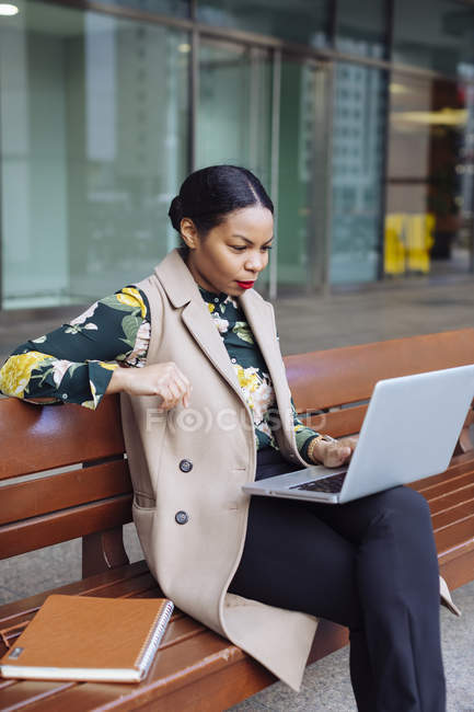 Mujer de negocios sentada en el banco y utilizando el ordenador portátil - foto de stock