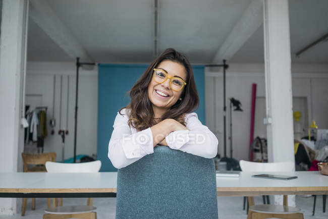 Портрет смеющейся девушки в очках, сидящей в студии — стоковое фото