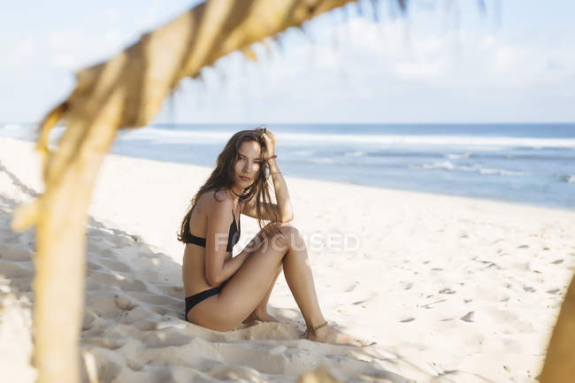 Індонезія, Балі, портрет привабливою молодої жінки, сидячи на пляжі — стокове фото