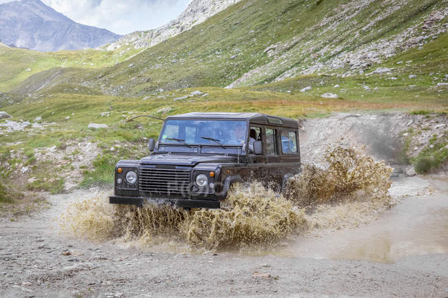 Italy, Piemont, Landrover driving through waterhole — Stock Photo