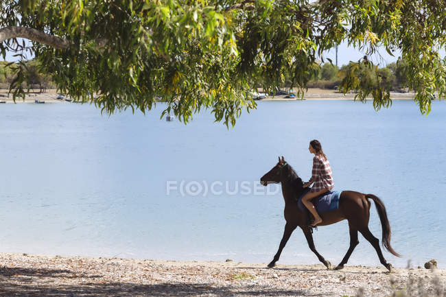 Indonésia, Bali, Mulher montando um cavalo na praia — Fotografia de Stock