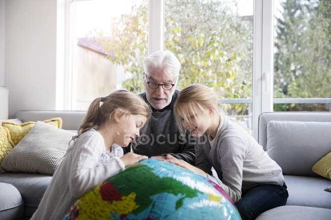 Due ragazze e nonno con globo in soggiorno — Foto stock