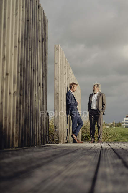 Due uomini d'affari in piedi sul lungomare e parlando — Foto stock