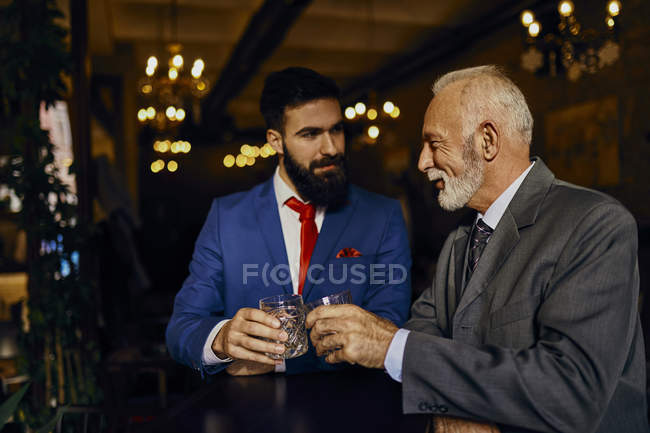 Due uomini eleganti in un bar che tintinnano bicchieri — Foto stock