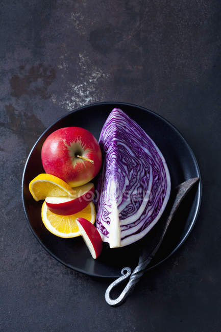 Pezzo fresco di cavolo viola con mela e arancia sul piatto su sfondo grunge scuro — Foto stock