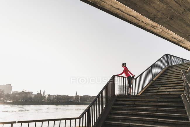 Giovane donna che si estende sulle scale di un fiume in città — Foto stock