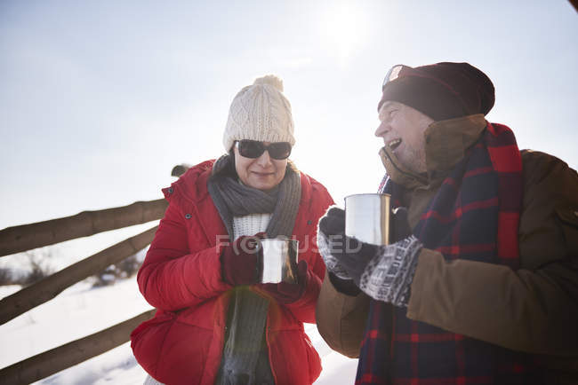 Счастливая зрелая пара с горячими напитками на открытом воздухе зимой — стоковое фото