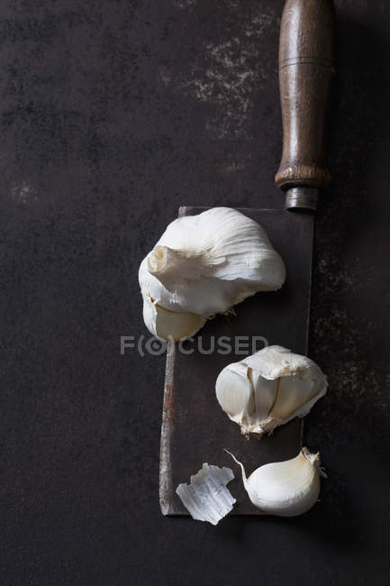 Aglio chiodi di garofano su mannaia arrugginita su sfondo grunge scuro — Foto stock