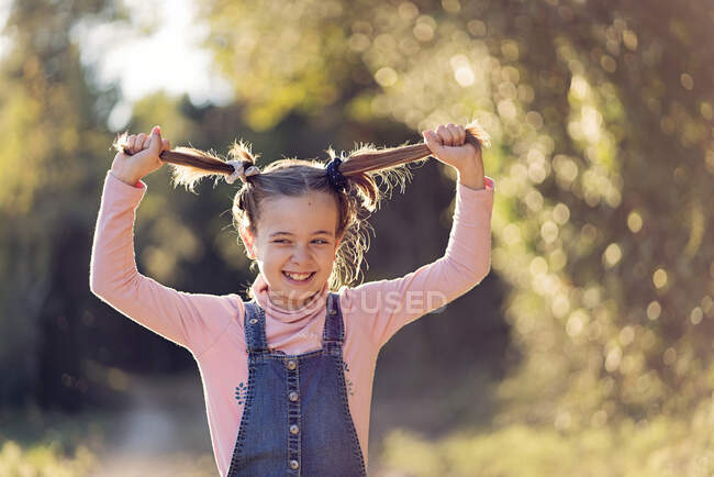 Retrato de niña riéndose tirando de su cabello - foto de stock
