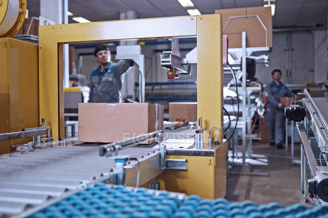 Men at work at conveyor belt in factory — Stock Photo
