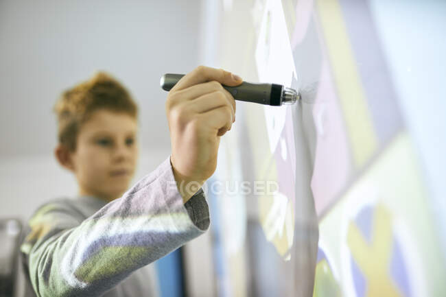 Студент у класі за допомогою оцифрованої ручки на інтерактивній дошці. — стокове фото